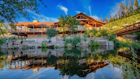 Wooden dining hall in front of blue skies reflects on river