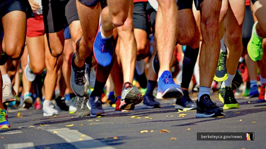 A close-up view of runners' legs and shoes in motion during a road race, with colorful sneakers on the street.
