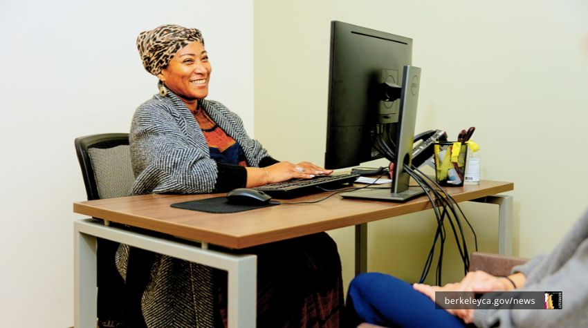 Smiling person sitting behind a desk talking to a patient