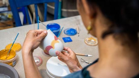 Person painting a ceramic cup